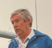 Professor Tony Marmont at West Beacon Farm with wind turbines in the background